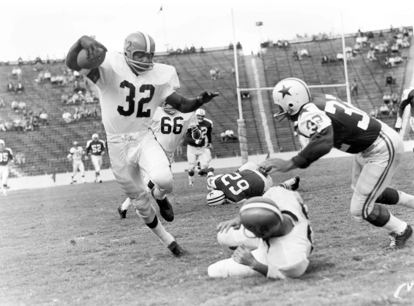 In this October 1960 file photo, Cleveland Browns fullback Jim Brown (32) runs with a reception as Dallas Cowboys' Tom Franckhauser (32) defends and Don Healy falls to the turf during an NFL football game in Dallas. (Associated Press)