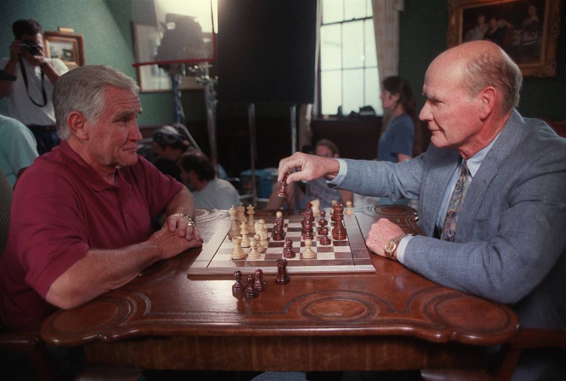 Former Miami Dolphins coach Don Shula (left) watches former Dallas Cowboys coach Tom Landry make a chess move on July 19, 1996, at Myers Park Country Club during the filming of a promotion for an NFL Films show called “Head Coach.” (Miami Herald Sun)