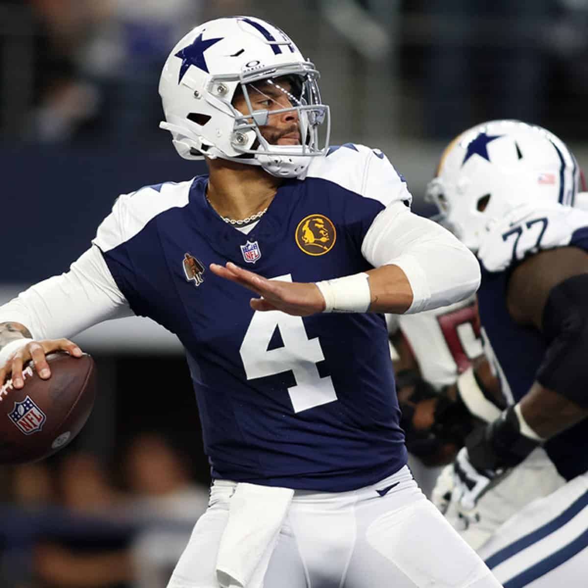 A football player wearing a blue and white jersey throwing a football