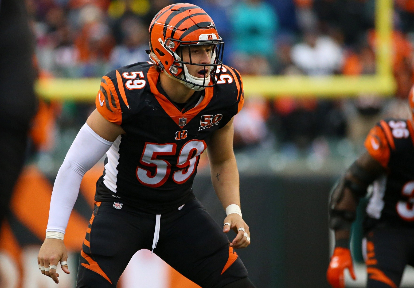 Football player in black and orange uniform with number 59 stands on the field, preparing for a play.