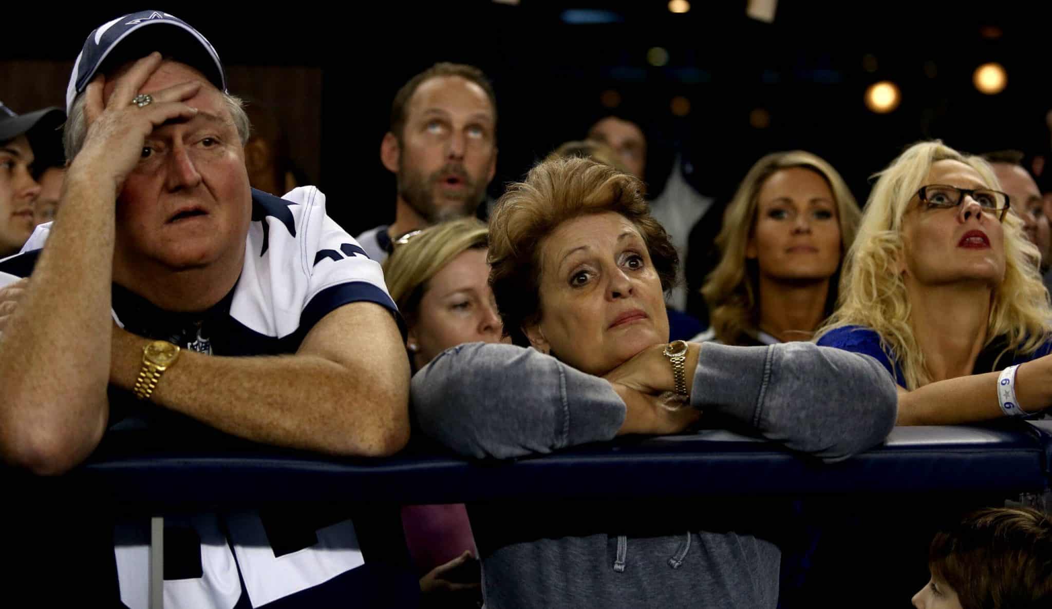 People look concerned and anxious while watching an intense sporting event.