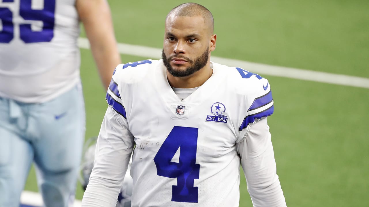 Football player in a white jersey with the number 4 stands on the field.