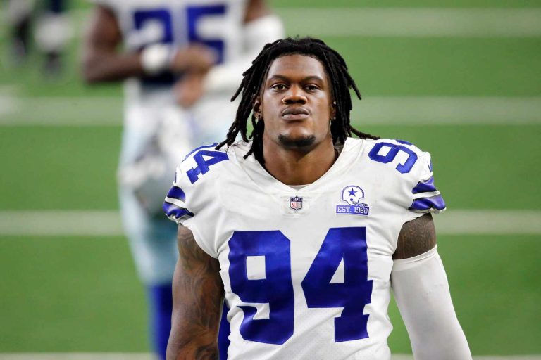 A football player wearing a white jersey with the number 94, standing on the field.