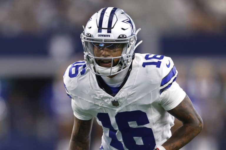 Football player in a blue and white uniform, wearing a helmet marked with "Cowboys," on the field during a game.