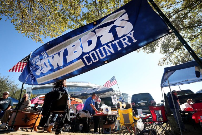 People tailgating under a "Cowboys Country" banner, with American flags and camping equipment visible in the background.