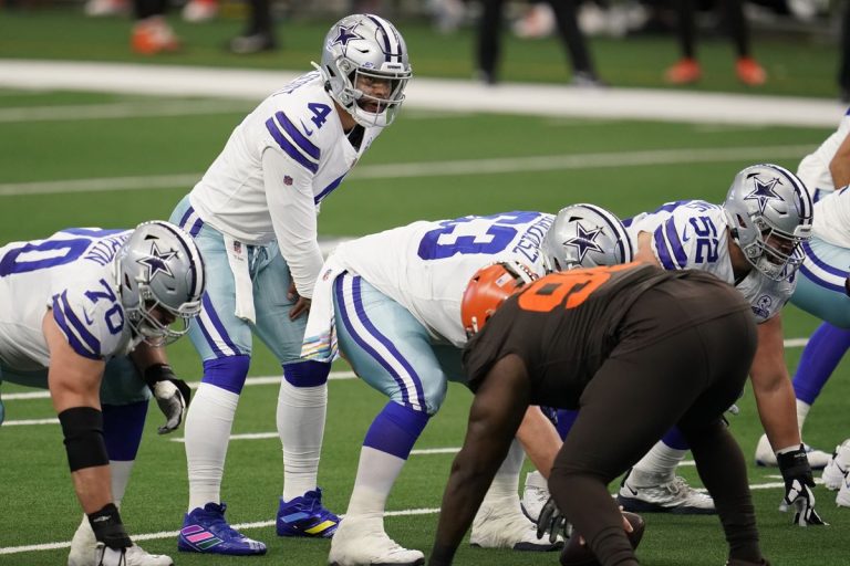 Football players from the Cowboys and Browns teams are lined up at the line of scrimmage during a game.